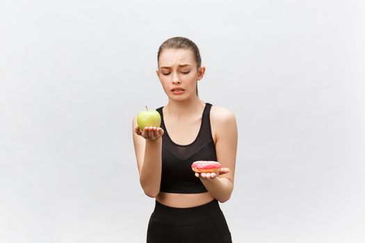 Young woman choosing between donut and apple on white background. Diet food concept