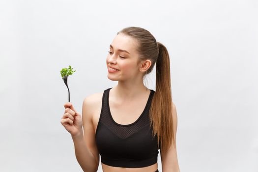 Young beautiful sport woman eating salad on white background.