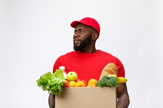 Portrait of delivery african american man in red shirt. he lifting heavy weight grocery boxes against having a isolated on the white background.
