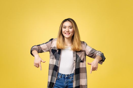 Smiling woman pointing finger side. Isolated portrait on yellow.