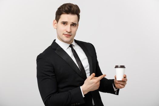 Business Concept: Half-length shot of handsome businessman in a suit holding a cup of coffee and pointing at it with his finger