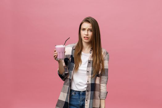 Disappointed young woman drinking smoothie juice. Isolated portrait.