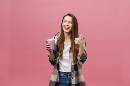 Young woman drinking juice smoothie with straw. Isolated studio portrait.