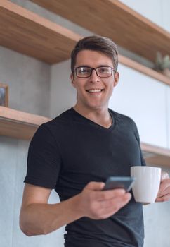 casual young man using smartphone in kitchen