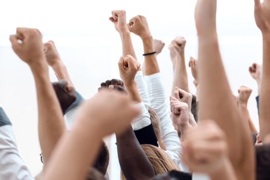 cropped image of a multiracial group of people holding their hands up.
