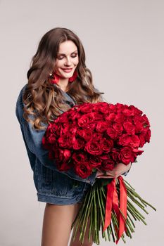 Gorgeous woman with big earings holding roses and smiling.