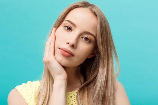 Beautiful Woman Face Portrait Beauty Skin Care Concept: beauty young caucasian female model girl touching her face skin cheeks hands fingers. Fashion Beauty Model isolated on blue.