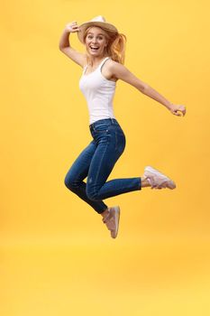 Happiness, dream, fun, joy, summer concept. Very excited happy cute caucasian teen is jumping up, in summer outfit, hat, on bright yellow background
