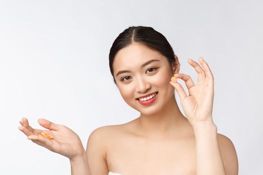 Young attractive asian woman who takes a capsule or pill. Isolated over white background.