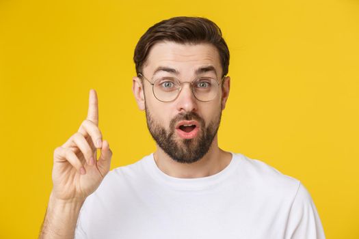 Young man looking at copyspace having a surprised or satisfied look isolated on yellow background.