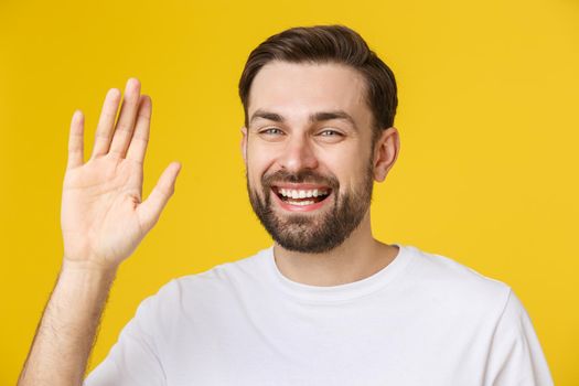 Hi, Hello. Portrait of happy friendly brown-haired man with small beard in white shirt waving hand to camera, welcoming with toothy smile.