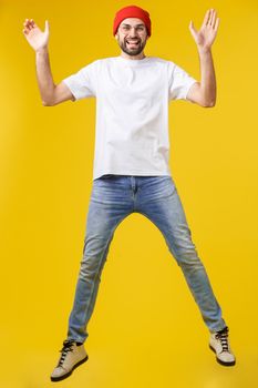 young casual man jumping for joy on yellow gold background
