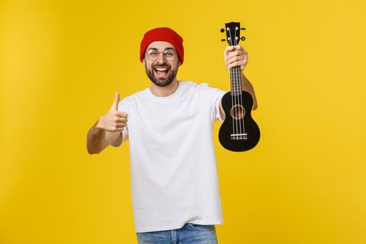 close-up of funny young man playing a guitar. isolated on yellow gold background
