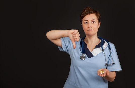 Frowning doctor woman showing disapproval sign-holding thumb down