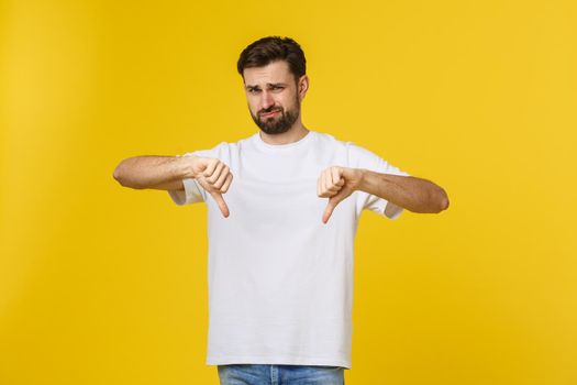 Young handsome man wearing white t-shirt over isolated background Doing thumbs down, disagreement and agreement expression. Crazy conflict.