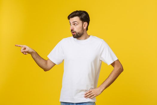 Handsome man over isolated yellow wall frustrated and pointing to the front.