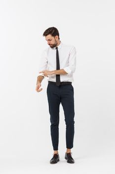 Portrait of a confident young businessman with hands in pockets on white background