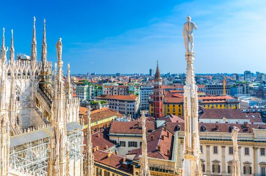 White marble statues figures on roof of famous Duomo di Milano Cathedral and top aerial view of Milan city centre
