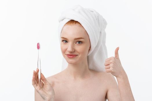 Portrait of young woman with toothbrush on grey background.