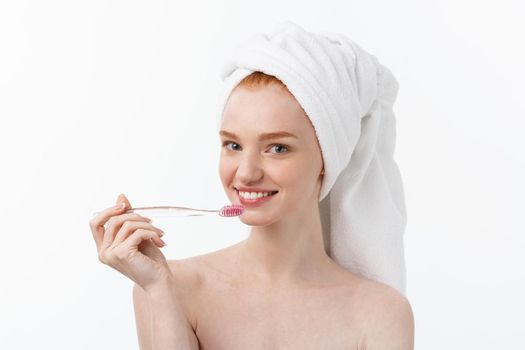 Portrait of young woman with toothbrush on grey background.