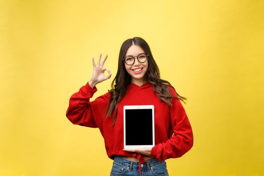 Woman using digital tablet computer PC isolated on yellow background