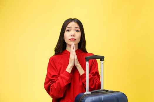 Dream about travel and vacation. Studio portrait of excited pretty young woman with praying hands. Isolated on yellow.