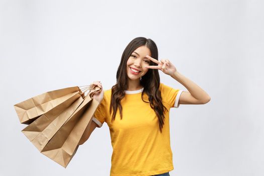 Young beautiful shopper woman with shopping bags shows two fingers. Isolated white background