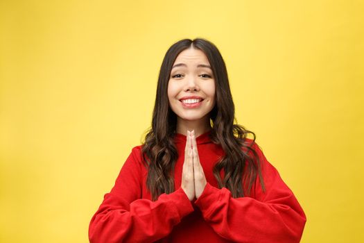 Getting concentration from space. Portrait of good-looking young european female, holding hands in pray, focused on wishing over yellow background