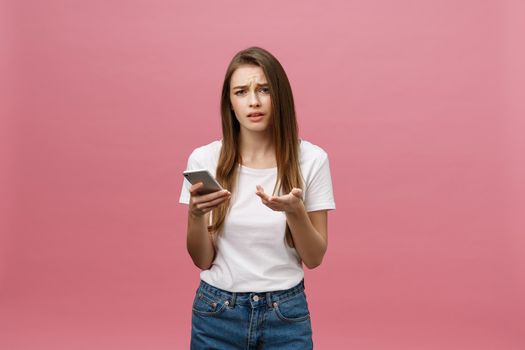 Serious young woman talking on phone isolated on pink. Copy space and fashion. Mock up.