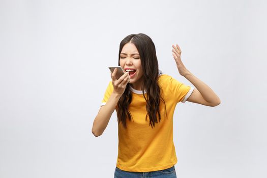 Portrait of a furious asian woman talking on mobile phone isolated over white background