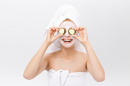 Portrait of the playful girl covering an eye by a slice of a cucumber, isolated on white.