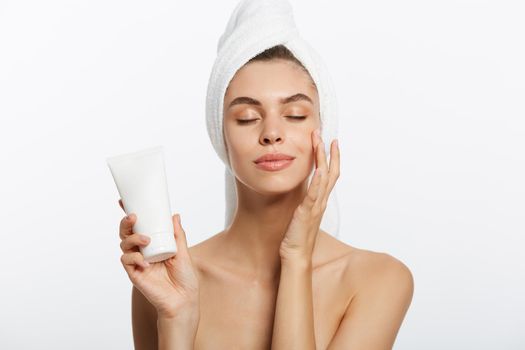Woman applying cream on shoulder on a white background.