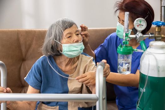 Elderly woman wearing oxygen nasal cannula at home.