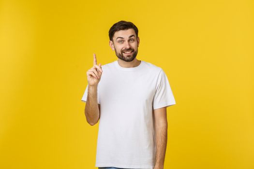 Young happy man gets good idea, raises fore finger as going to voice it, being glad have genius thoughts in mind, isolated over white background.