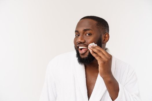 Smiling african man apply cleansing his face. Man's skin care concept
