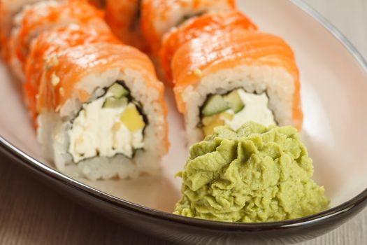 Close up wasabi and sushi rolls - Uramaki Philadelphia on the background
