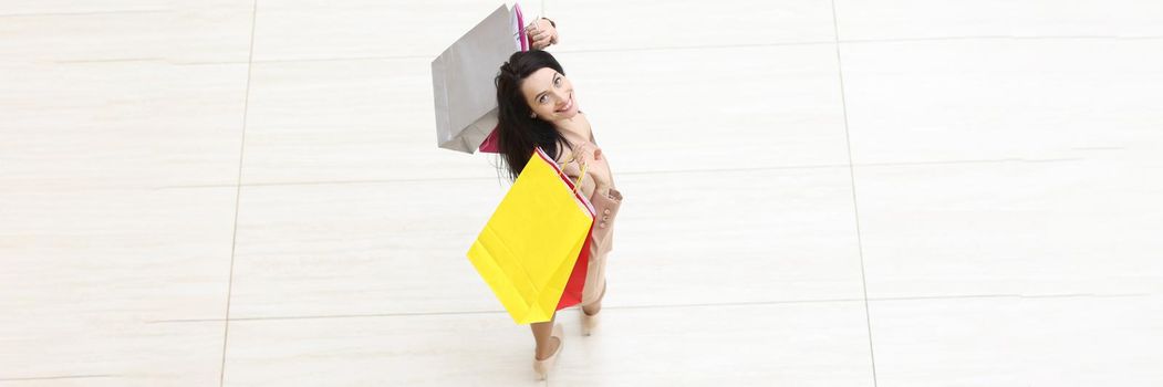 Happy woman with packages on floor of shopping mall