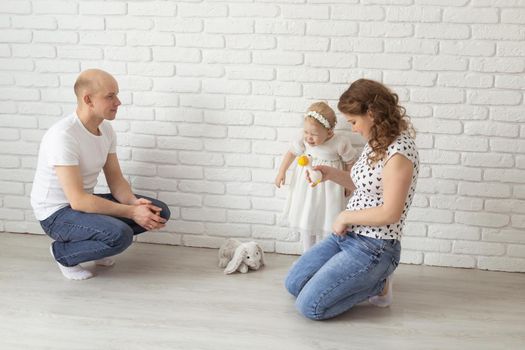 Baby child with hearing aids and cochlear implants plays with parents on floor. Deaf and rehabilitation and diversity concept