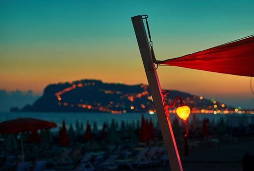 Lantern on the beach at sunset with Alanya peninsula on the background