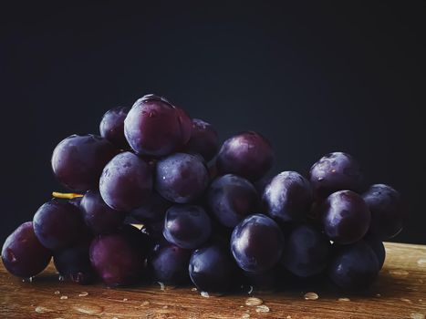 Ripe juicy dark grapes on wooden desk, food and wine, organic fruits