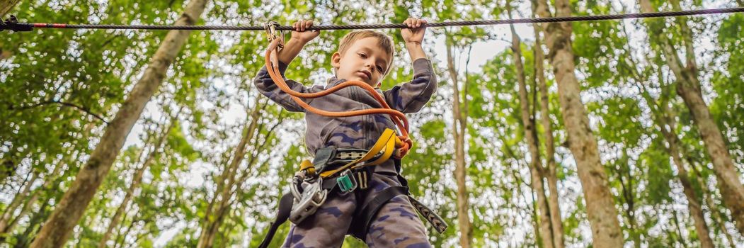 Little boy in a rope park. Active physical recreation of the child in the fresh air in the park. Training for children BANNER, LONG FORMAT