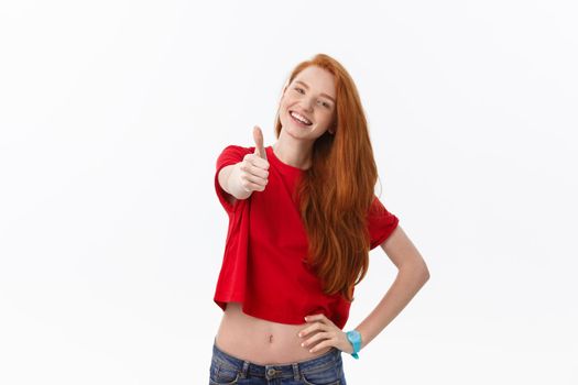 Happy young caucasian female making thumb up sign and smiling cheerfully, showing her support and respect to someone.