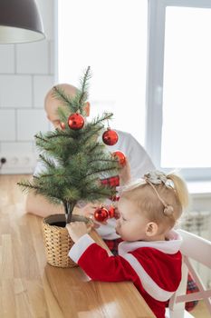 Child with cochlear implant hearing aid having fun with father and small christmas tree - diversity and deafness treatment and medical innovative technologies