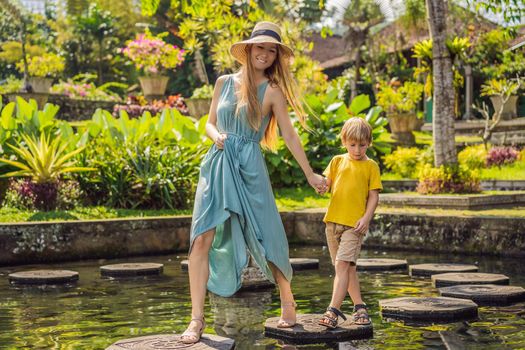 Mom and son tourists in Taman Tirtagangga, Water palace, Water park, Bali Indonesia. Traveling with children concept. Kids friendly place
