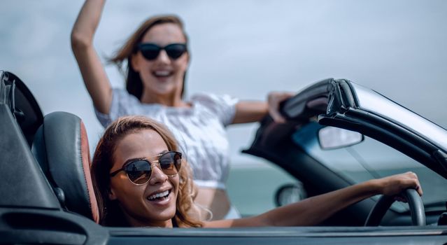 close up.two happy young women in a convertible car