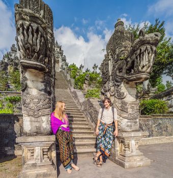 Happy couple of tourists on background of Three stone ladders in beautiful Pura Lempuyang Luhur temple. Summer landscape with stairs to temple. Paduraksa portals marking entrance to middle sanctum jaba tengah of Pura Penataran Agung, Bali