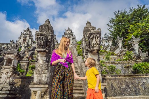 Mother and son tourists on background of Three stone ladders in beautiful Pura Lempuyang Luhur temple. Summer landscape with stairs to temple. Paduraksa portals marking entrance to middle sanctum jaba tengah of Pura Penataran Agung, Bali. Traveling with children concept. Kids friendly place