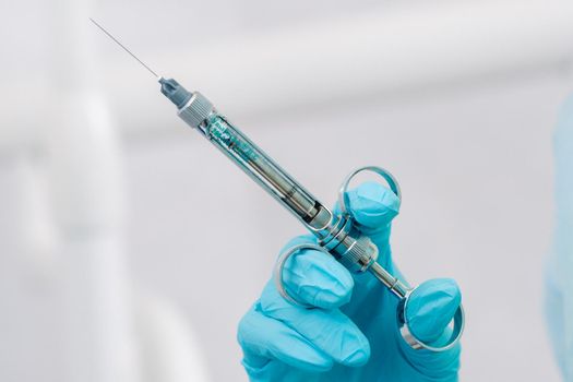 close-up of a dentist's hand holding an injection syringe for a patient in the office