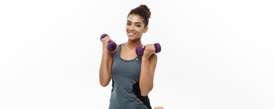 Healthy and Fitness concept - Beautiful American African lady in fitness clothes workout with dumbbell. Isolated on white background.