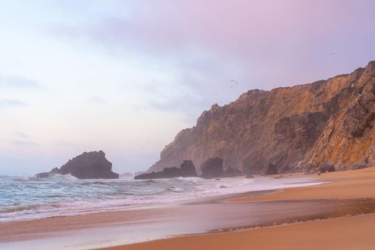 Ocean wild beach stormy weather. Praia da Adraga sandy beach with picturesque landscape background, Sintra Cascais, Portugal
